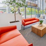 Espace d'attente lumineux avec canapés orange et mobilier en bois naturel pour entreprises