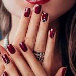 Nail art élégant avec strass sur vernis bordeaux scintillant, création de l'espace onglerie de XXL Coiffure Annemasse