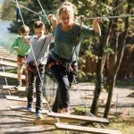 Famille traversant un pont suspendu dans le parcours aventure du parc