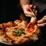 Découpe d’une pizza napolitaine fraîchement cuite au restaurant Da Renato