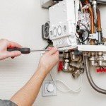 Artisan chauffagiste de Dépan’Services Gaz & Eau réparant l'intérieur d'une chaudière murale au gaz