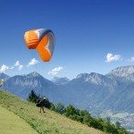 Décollage d’un parapentiste dont les pieds s’élèvent du sol, début du vol en parapente