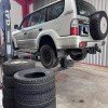Grand SUV Land Cruiser sur un pont élévateur pour le changement de courroie de distribution et de pneus chez MonsieurPneus à Amancy.