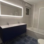 Meuble vasque sombre et miroir lumineux dans une salle de bains, rénovation intérieure à Annemasse par Liberté Patrimoine Rénovation