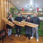 Équipe du restaurant Sushi & Kimchi présentant de grands plateaux de sushis à emporter ou en livraison