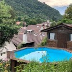 Vue sur piscine extérieure et village de montagne, un bien géré par Prestige Home Partner conciergerie Haute-Savoie
