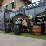 Terrasse extérieure du Double Concept avec tables en tonneaux, parfaite pour un apéritif