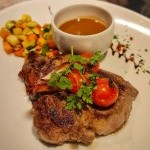 Pièce de bœuf grillée avec sauce et petits légumes glacés au restaurant bord du lac Le Redon