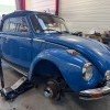 Garage MonsieurPneus Amancy, spécialiste de la réparation d'embrayage, soulevant une Coccinelle bleue pour intervention.