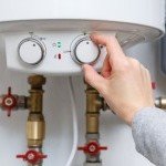 Chauffagiste de chez Dépan’Services Gaz & Eau réglant le thermostat d'un chauffe-eau électrique mural à Thonon-les-Bains.