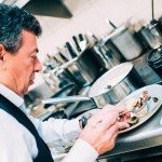 Le chef Christian Constant dressant une assiette gastronomique en cuisine