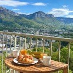 Petit-déjeuner sur un balcon avec vue panoramique sur les montagnes de Cluses, gestion locative GoldenKeys