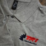 Zoom sur broderie personnalisée TRI Distribution sur la poitrine d'un polo gris SOL'S par un professionnel du flocage textile